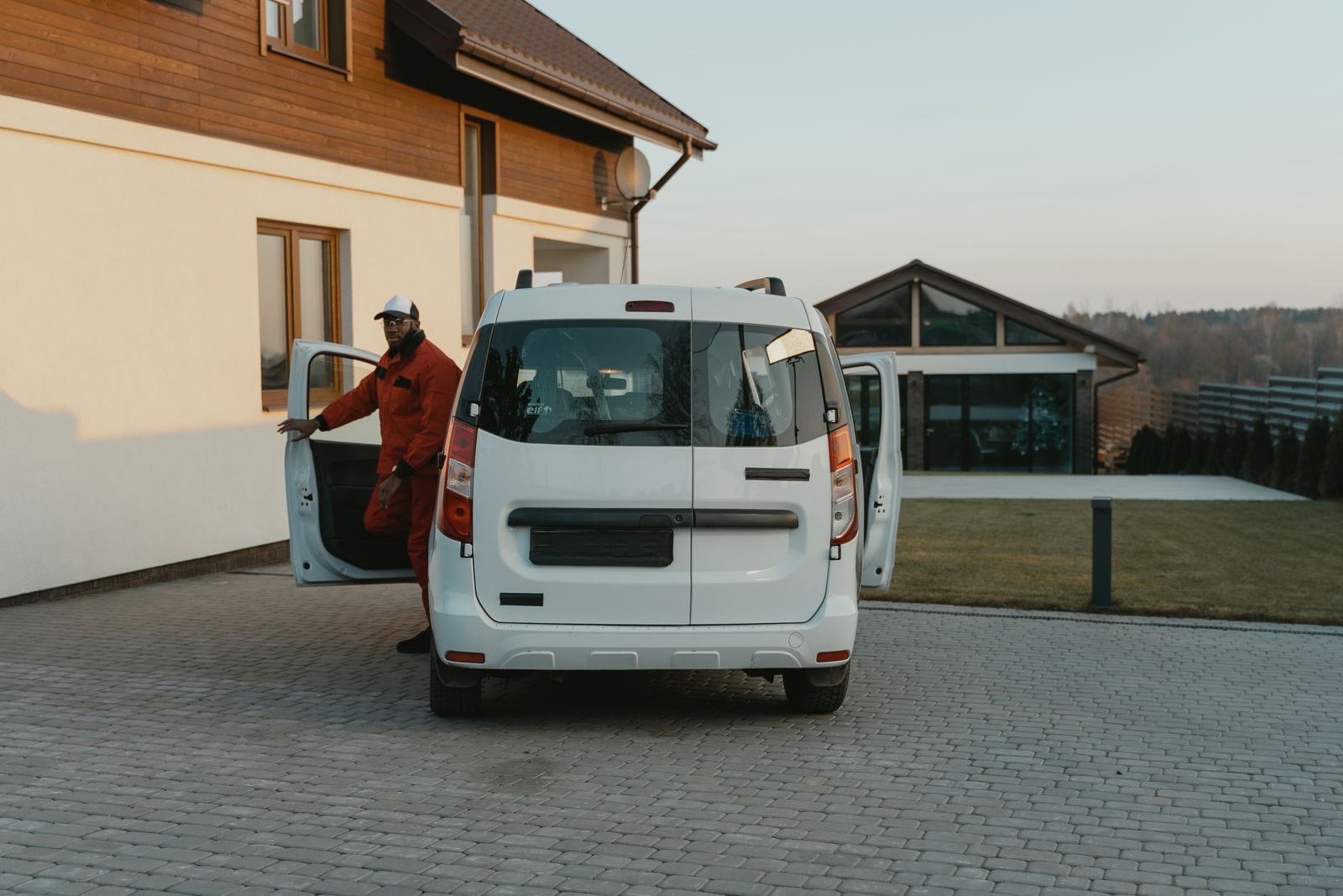 A service worker stepping out of a work van in a driveway