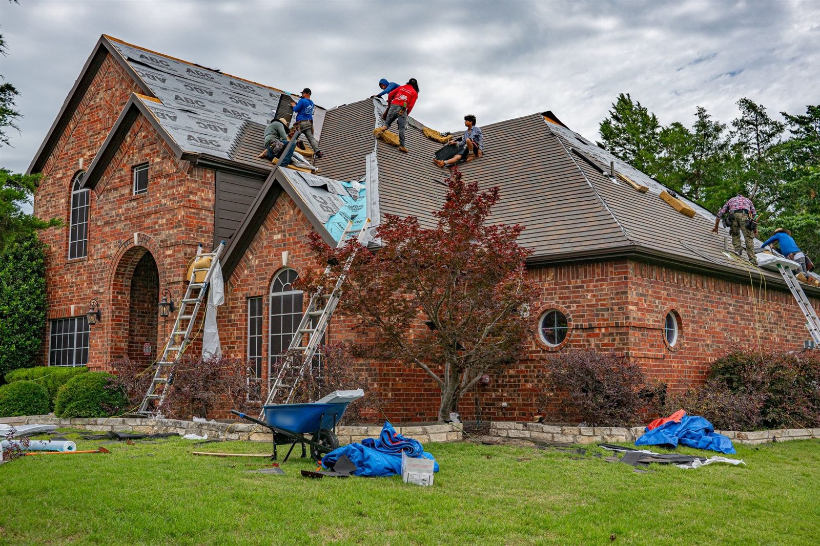 A crew working on the roof of a brick house