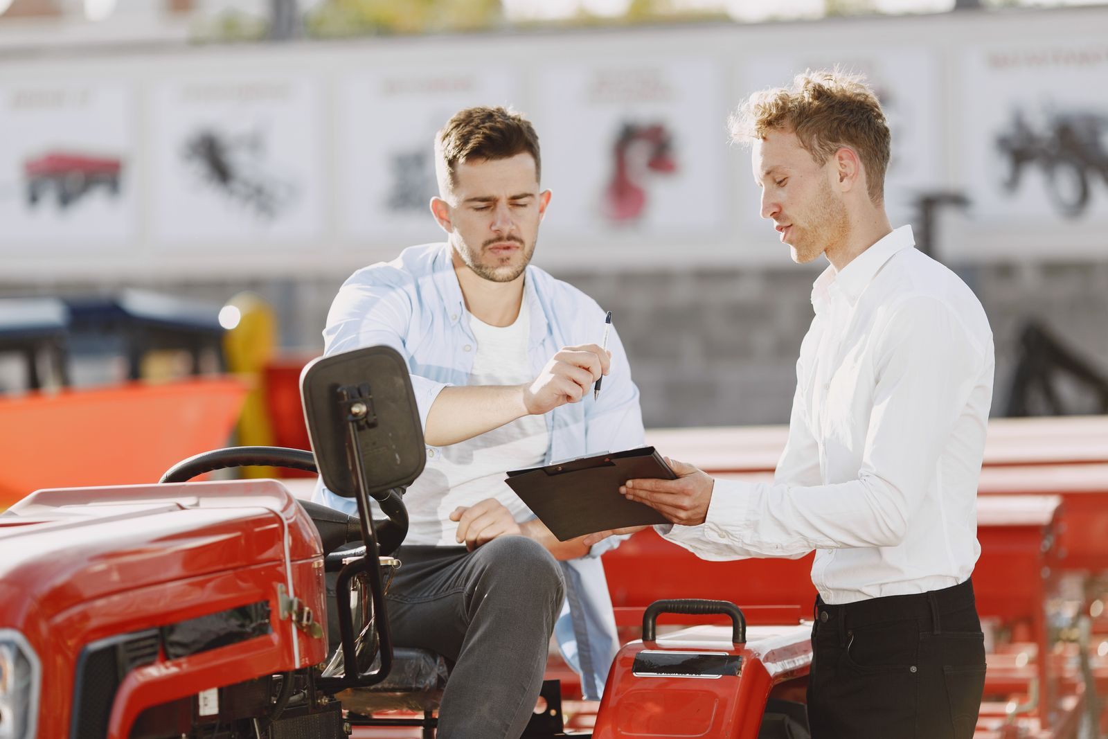 Two men going over paperwork together beside a tractor